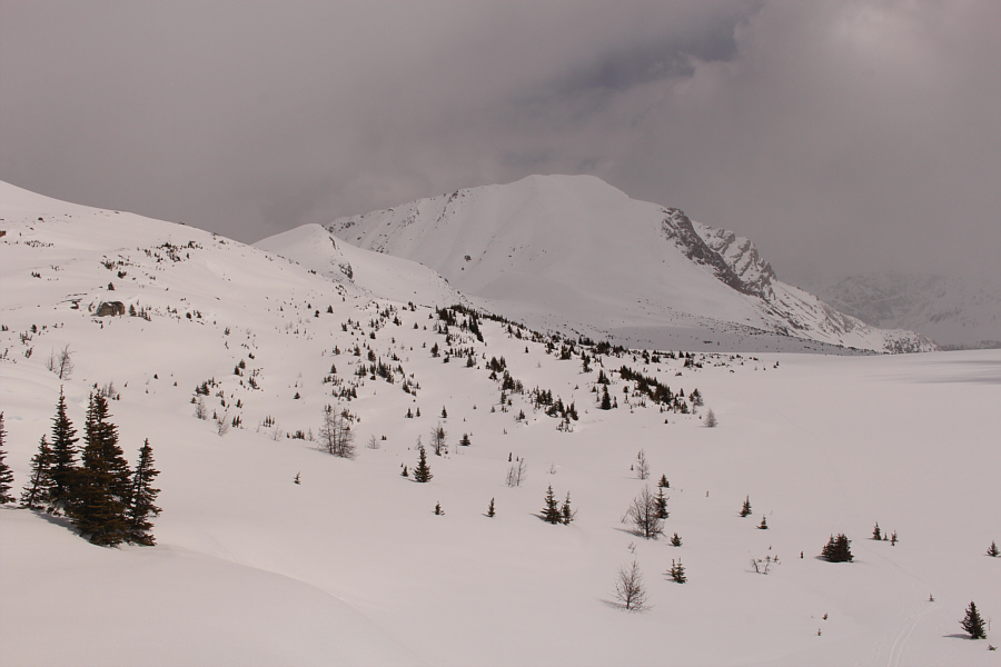 The safest ascent line drops down to the lake and rises through the trees at centre.